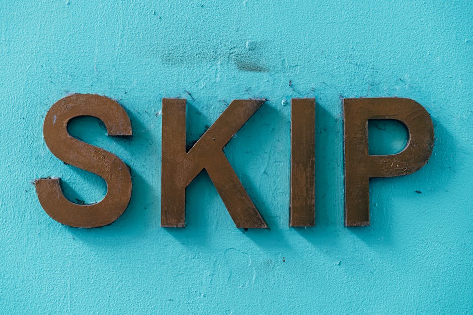 A close-up view of three three-dimensional, metallic letters spelling 'SKIP' mounted on a textured, light turquoise wall. The letters are brown with a matte finish and are arranged in a straight line,
